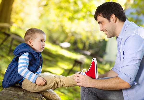 Little boy is tying his father's shoes