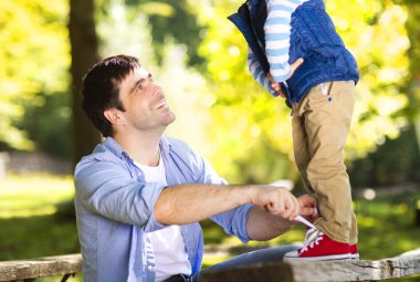 Baba oğlu ayakkabılarını yardımcı oluyor