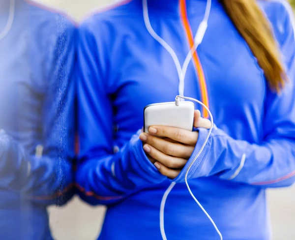 Runner is having break and listening to music — Stock Photo, Image