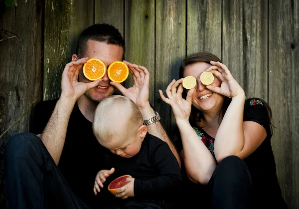 Familj med liten pojke att ha kul med apelsiner — Stockfoto