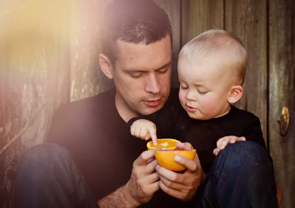 Vater mit Sohn beim Orangenessen — Stockfoto