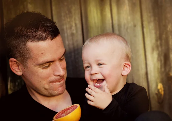 Pai com filho comendo laranja — Fotografia de Stock
