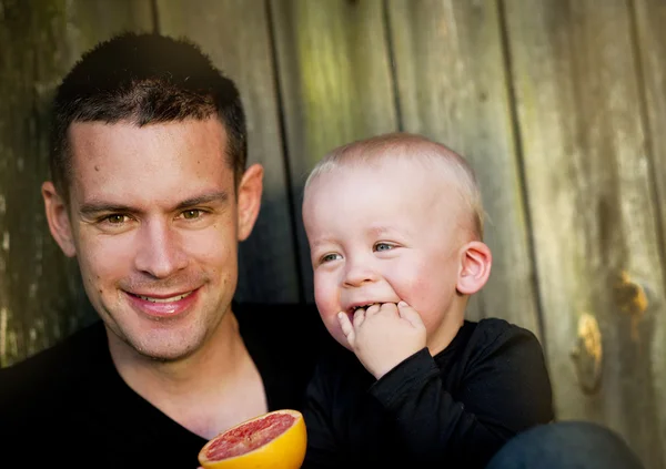 Vader en zoon eten oranje — Stockfoto