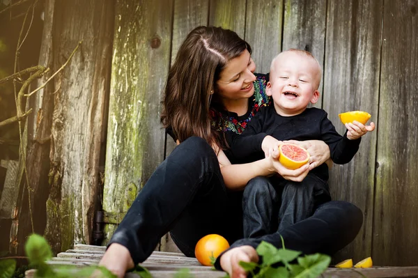 Moeder en zoontje eten oranje — Stockfoto