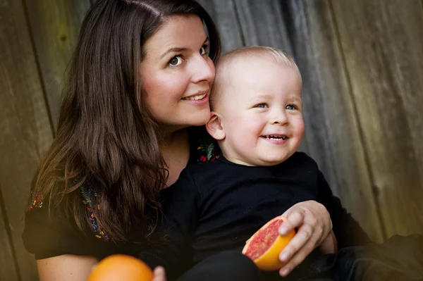 Mãe e filho pequeno comendo laranja — Fotografia de Stock