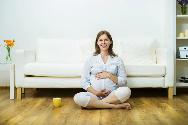 Gravid kvinna sitter på golvet — Stockfoto