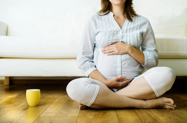 Zwangere vrouw zittend op de bank — Stockfoto