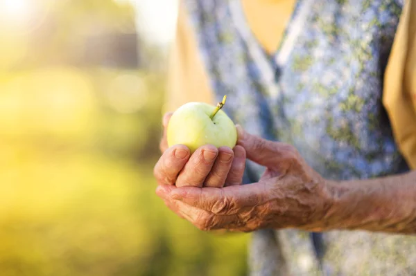 Senior woman eten apple — Stockfoto