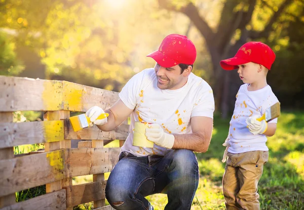 Pai com filho pintando cerca de madeira — Fotografia de Stock