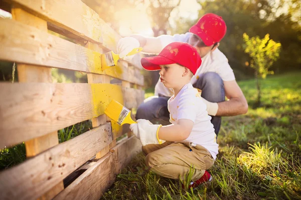 Pai com filho pintando cerca de madeira — Fotografia de Stock