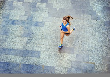 Female runner jogging on tiled pavement clipart