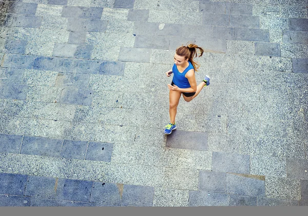 Läuferin joggt auf gefliestem Bürgersteig — Stockfoto