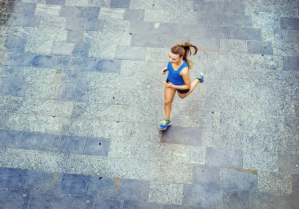 Female runner jogging on tiled pavement — Stock Photo, Image