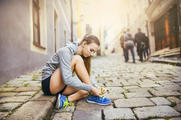 Vrouwelijke atleet is koppelverkoop haar loopschoenen — Stockfoto