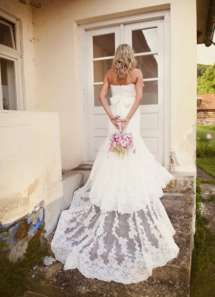Sposa con velo posa da vecchia casa — Foto Stock