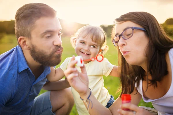 Fille avec ses parents souffler des bulles — Photo