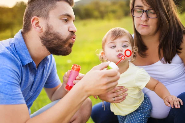 Flicka med hennes föräldrar blåser bubblor — Stockfoto