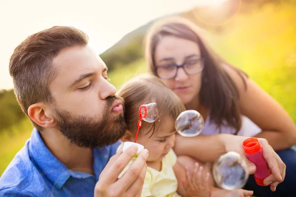 Chica con sus padres soplando burbujas — Foto de Stock