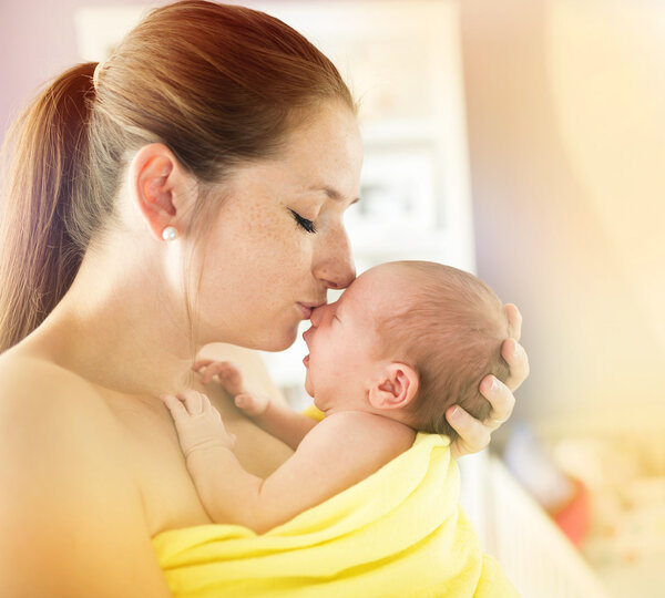 Mother kissing her newborn baby girl