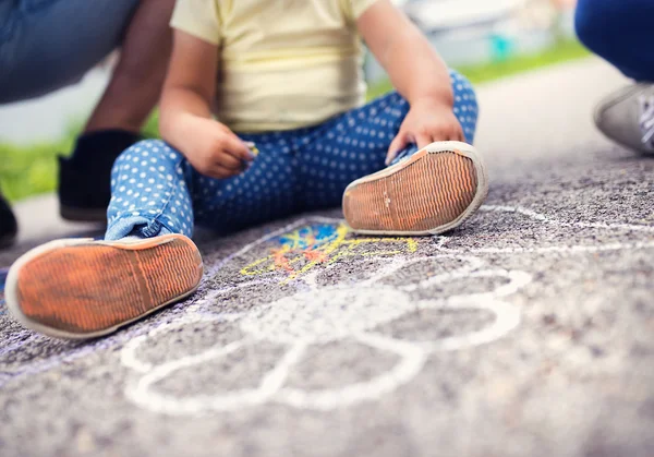 Flicka rita med kritor på trottoaren — Stockfoto