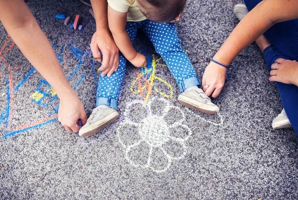 Little girl and parents drawing on the sidewalk — Stock Photo, Image