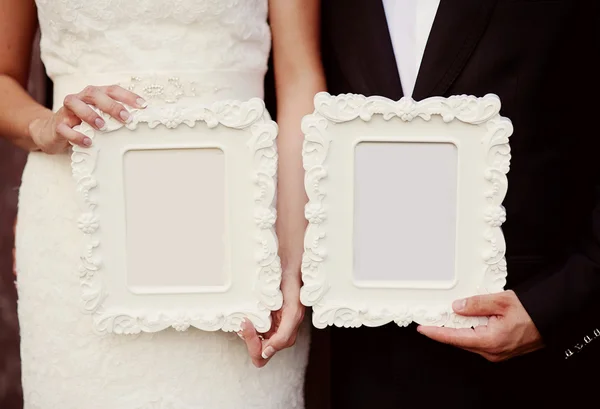 Bride and groom holding vintage photo frames — Stock Photo, Image