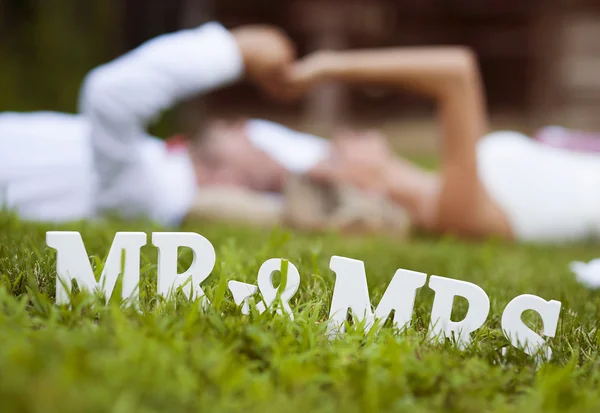 Bride and groom lying on grass — Stock Photo, Image