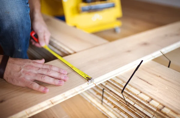 Manos que miden suelos de madera — Foto de Stock