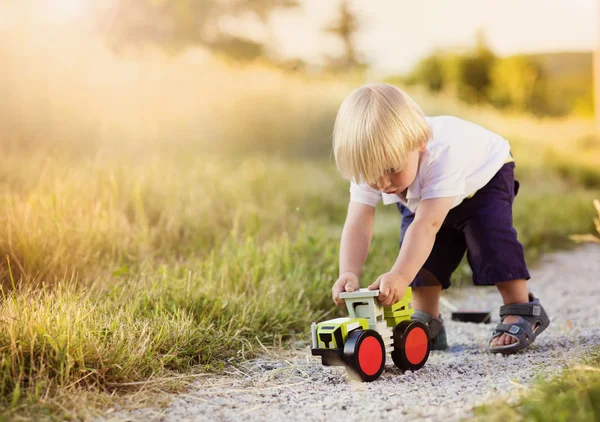 Мальчик играет с игрушечным трактором — стоковое фото