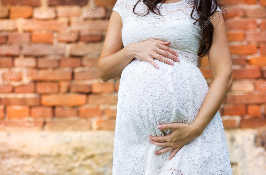 Beautiful pregnant woman in white dress