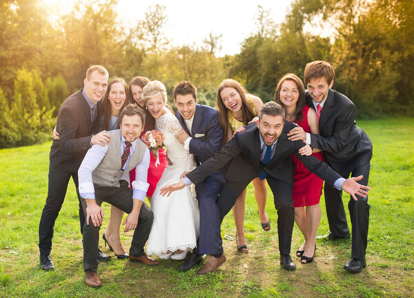 Newlywed couple having fun with bridesmaids and groomsmen