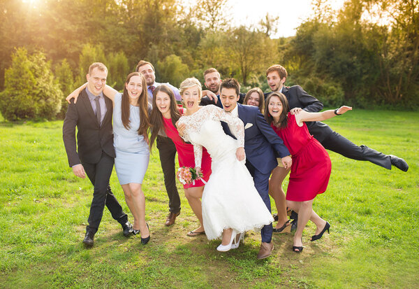 Newlywed couple having fun with bridesmaids and groomsmen