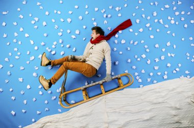 Young man on sled having fun clipart