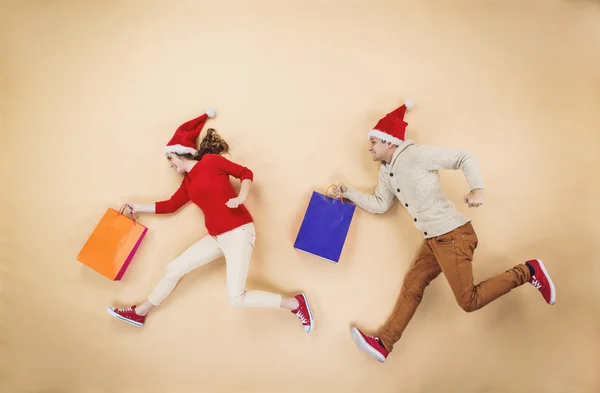 Par i jul hattar kör med kassar och påsar — Stockfoto