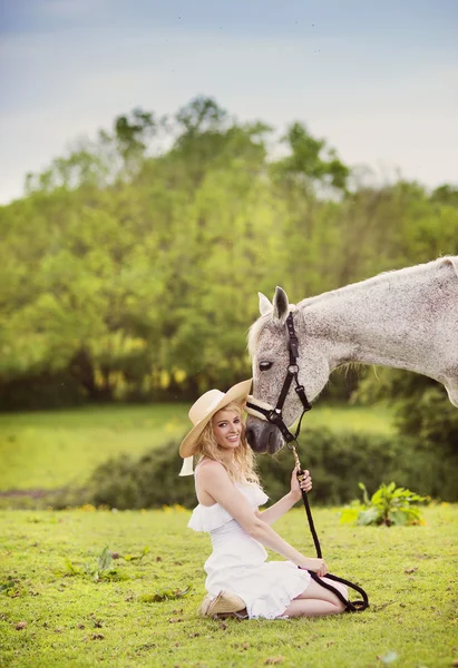 Mulher sentada com cavalo no campo — Fotografia de Stock