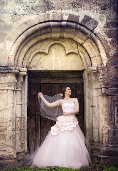 Bride standing by old chapel. — Stock Photo, Image