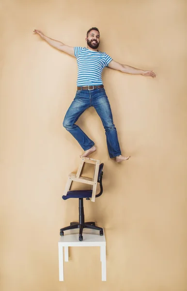 Mann steht gefährlich auf Stapel von Stühlen. — Stockfoto