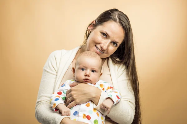 Madre sosteniendo un bebé tiernamente en sus brazos — Foto de Stock