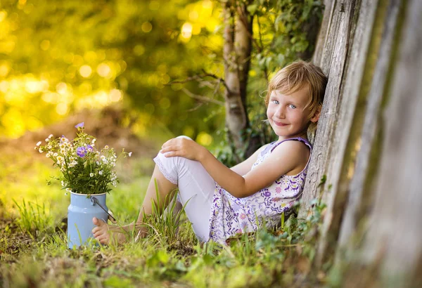 Meisje zit met weide bloemen — Stockfoto