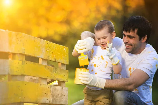 Menino e seu pai pintando cerca de madeira — Fotografia de Stock