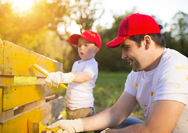 Father with son painting wooden fence — Stock Photo, Image