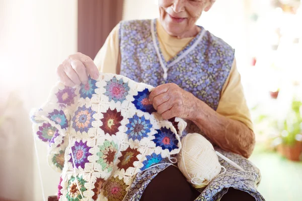 Old woman is knitting a blanket — Stock Photo, Image