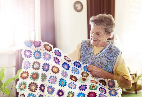 Old woman is knitting a blanket — Stock Photo, Image
