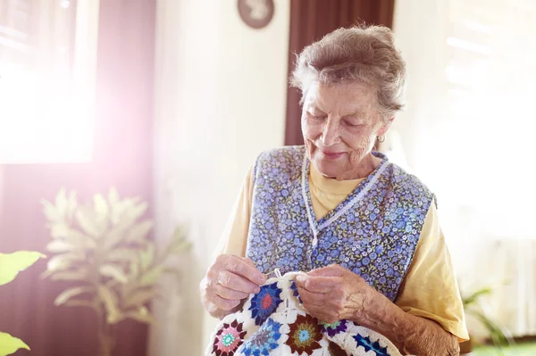 Old woman is knitting a blanket — Stock Photo, Image