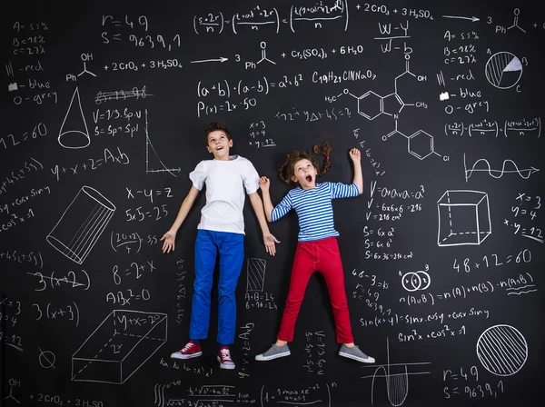 Garçon et fille apprenant devant un tableau noir — Photo