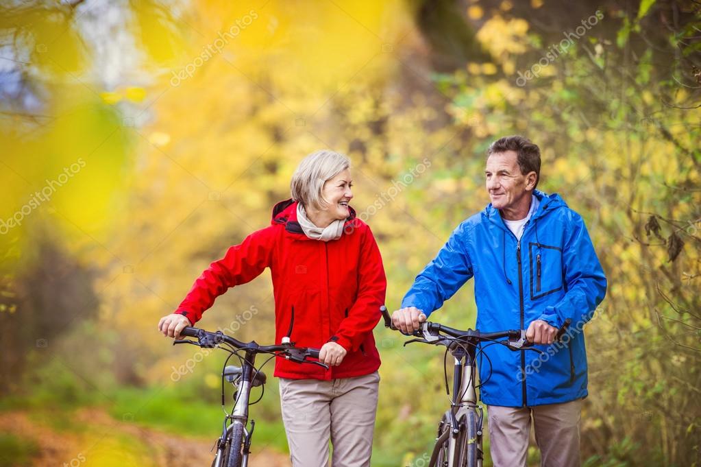Пенсионеры осенью. Прогулка пожилых. Пожилая пара на велосипедах. Прогулки на свежем воздухе. Велосипед для пенсионеров.