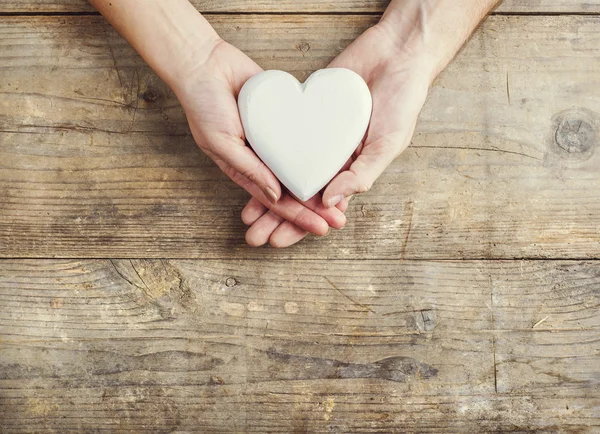 Manos de hombre y mujer sosteniendo un corazón unido — Foto de Stock