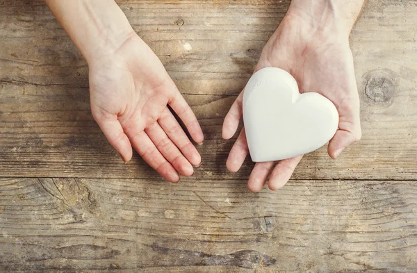 Hands of man and woman holding a heart together — Stock Photo, Image