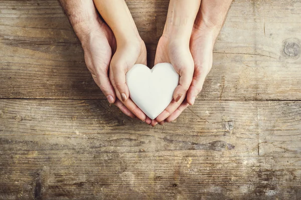 Manos de hombre y mujer sosteniendo un corazón unido — Foto de Stock