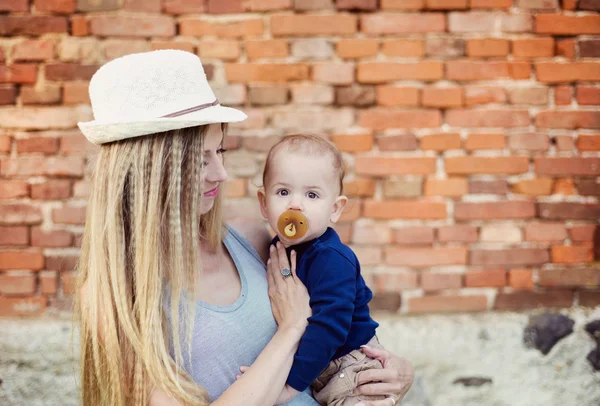 Mãe com seu filho bebê pela parede de tijolo . — Fotografia de Stock